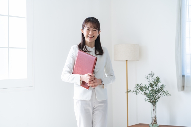 資料を手にして立つ女性。リフォームの相談を終えたイメージ