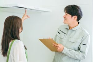 キッチンのレンジフードについてリフォーム会社の担当者に相談する女性