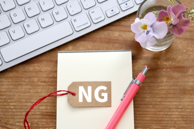 パソコンのキーボードの横に置かれた、NGと書かれた木の札