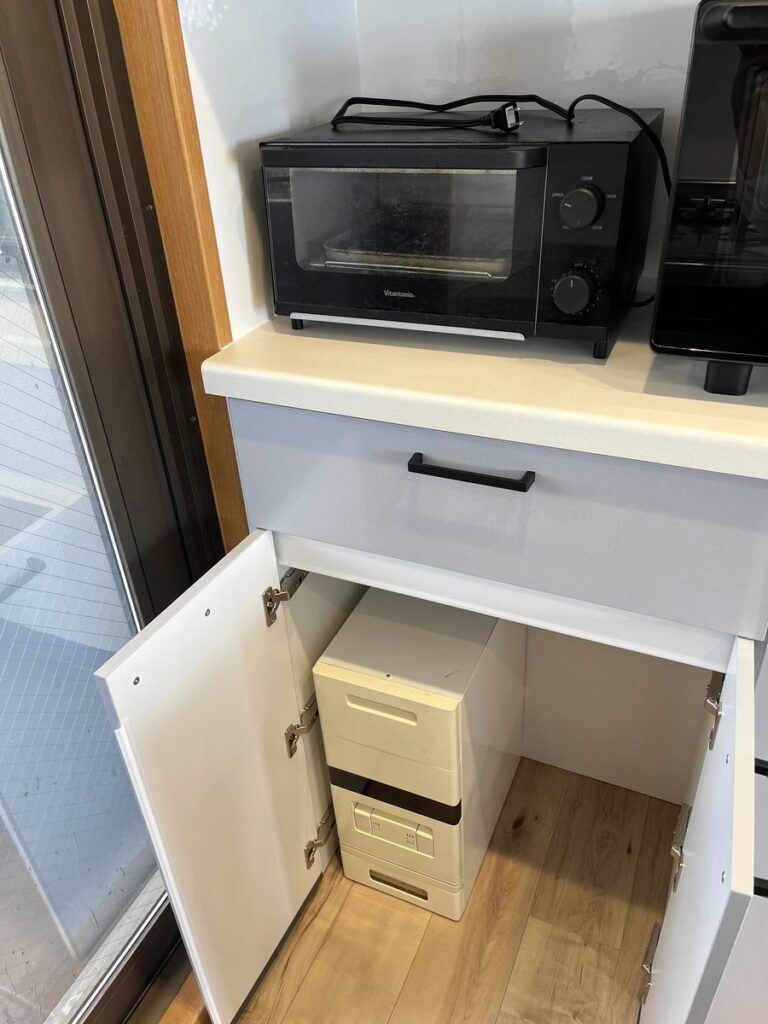 食器棚の下の収納。ゴミ箱用のオープン部分を開き戸に変えて米櫃を2つ入れた