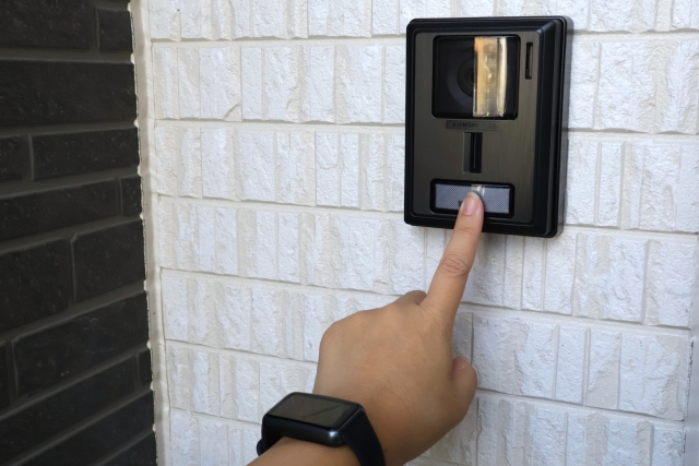 突然の訪問。マンションの玄関でインターホンを押す手