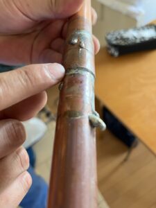 水漏れの原因になった銅製の給湯管。調査業者が取り外して見せてくれたもの