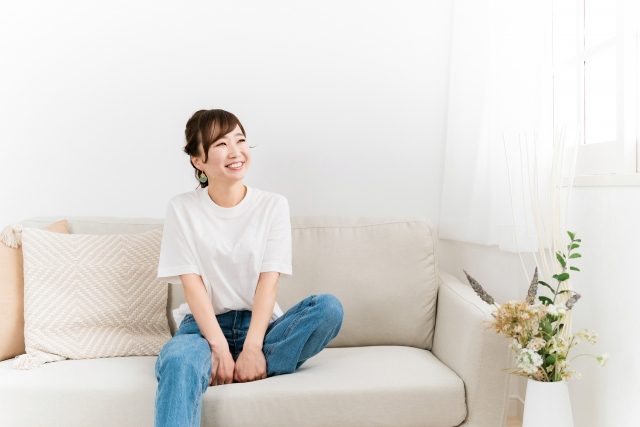 ソファに座ってくつろぐ女性と明るいリビング